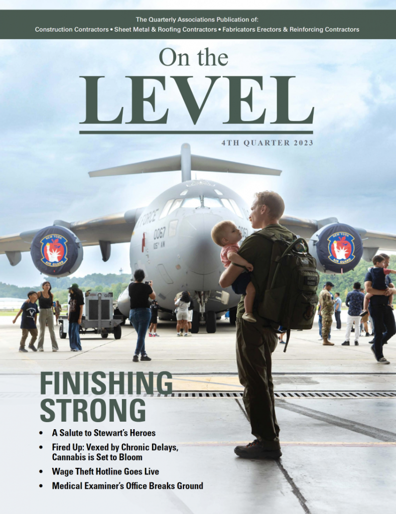 The cover of On the Level magazine with a photo of a man holding a baby. A large military cargo plane is in the background